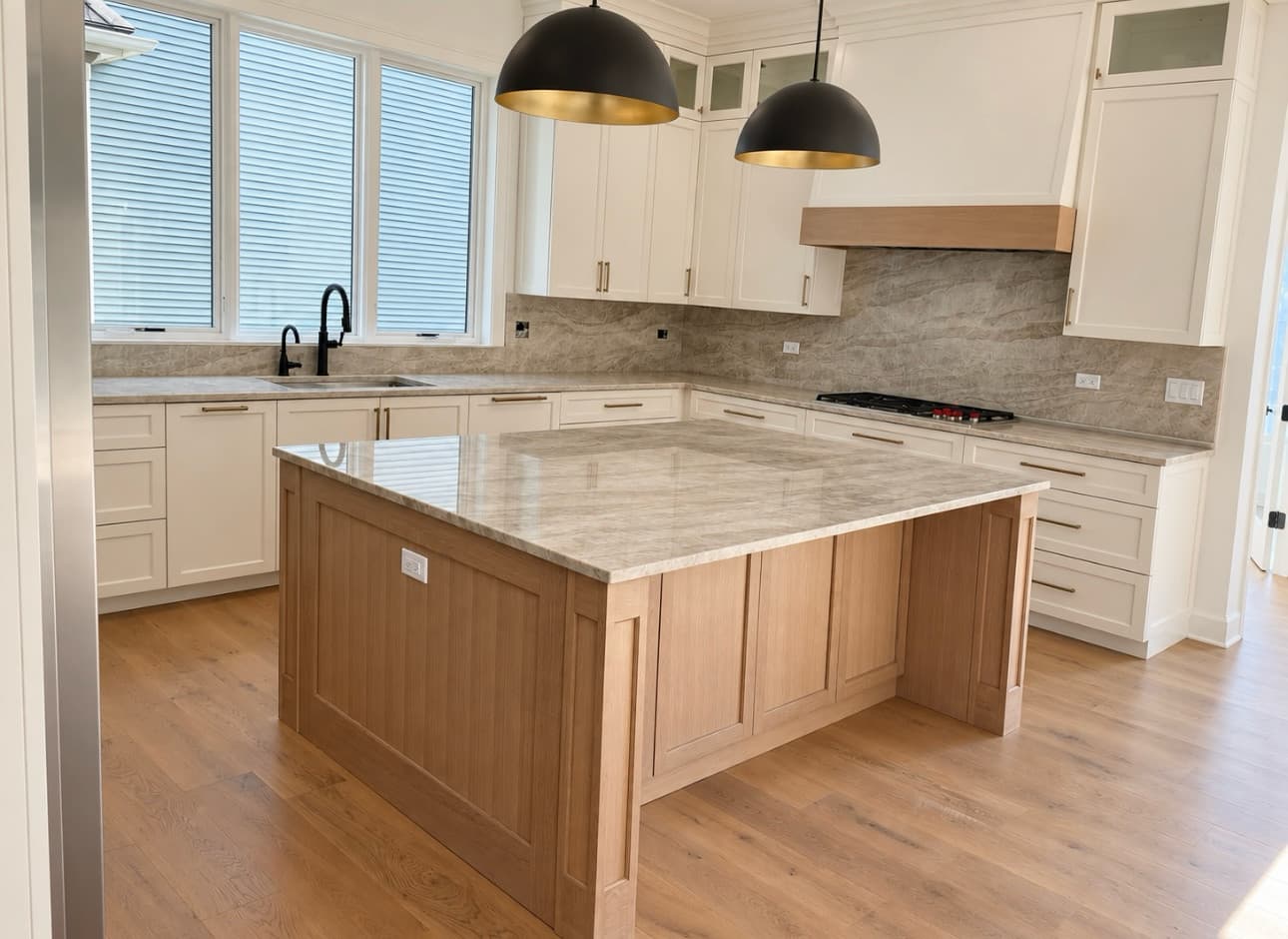 A stone-topped kitchen island and a stone backsplash in a white kitchen